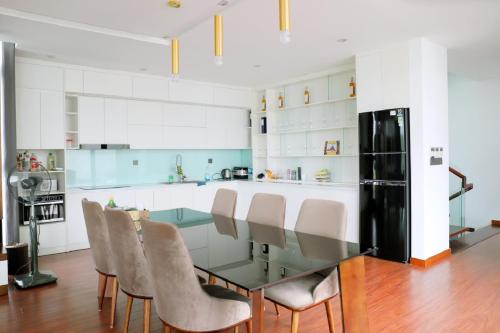 a kitchen with a glass table and chairs at FLAMIGO ĐẠI LẢI RESORT - Villa View Hồ in Ngọc Quang