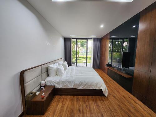 a bedroom with a bed and a television in it at FLAMIGO ĐẠI LẢI RESORT - Villa View Hồ in Ngọc Quang