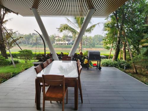 a table and chairs on a patio with trees at FLAMIGO ĐẠI LẢI RESORT - Villa View Hồ in Ngọc Quang