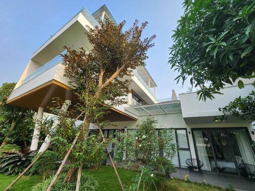 a house with trees in front of it at FLAMIGO ĐẠI LẢI RESORT - Villa View Hồ in Ngọc Quang