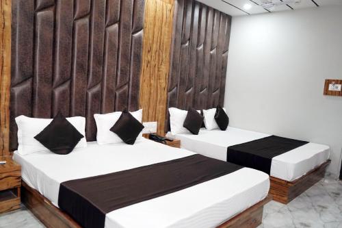 two beds in a hotel room with white and black at HOTEL PR VILLA in Gandhinagar
