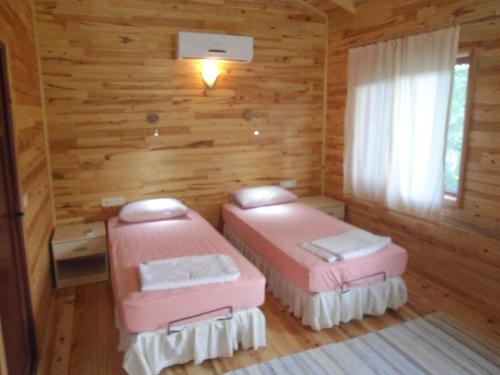 2 letti rosa in una camera con pareti in legno di Bungalow Halil a Çıralı