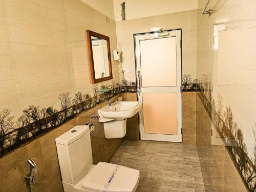 a bathroom with a toilet and a sink and a mirror at Gamodh Citadel Resort in Anuradhapura