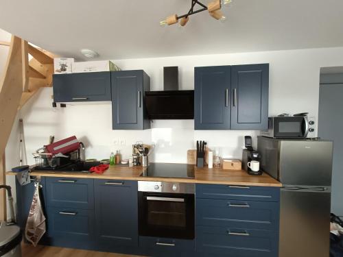 a kitchen with blue cabinets and a wooden counter top at Duplex F2 au pied des pistes du lac blanc in Orbey