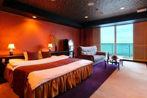 a large bedroom with a large bed and a chair at HOTEL CALM Leisure Hotel in Beppu