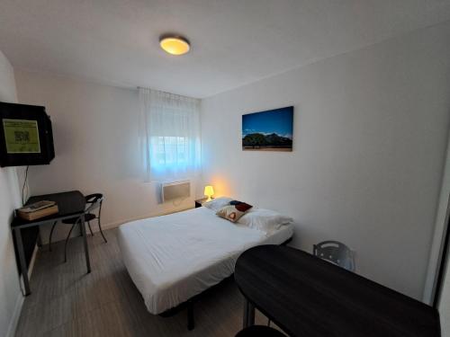 Habitación pequeña con 2 camas, mesa y escritorio. en Résidence Les Académies Aixoise, en Aix-en-Provence