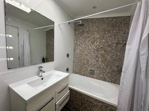 La salle de bains est pourvue d'un lavabo, d'une baignoire et d'un miroir. dans l'établissement 3 Bedroom House Family Friendly Surry Hills 2 E-Bikes Included, à Sydney