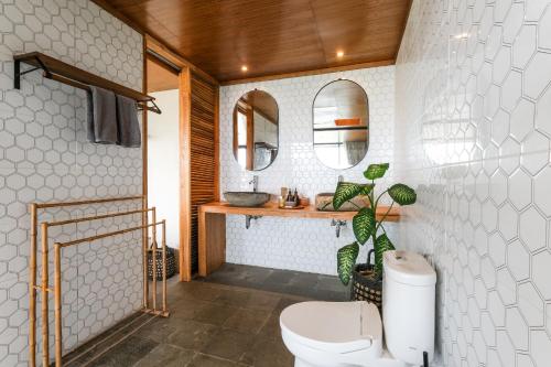 a bathroom with a toilet and two mirrors at The Elementum in Uluwatu