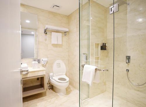 a bathroom with a toilet and a glass shower at Platinum Hotel Jimbaran Beach Bali in Jimbaran