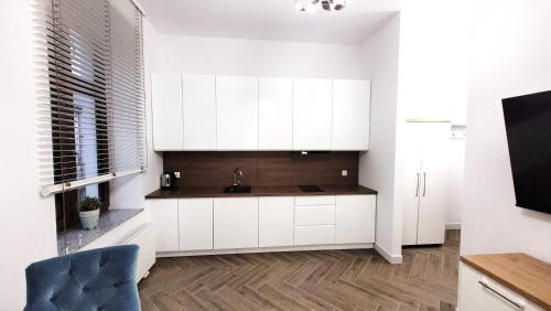 a kitchen with white cabinets and a sink at Apartament Jaracza 28 nr 6 in Słupsk