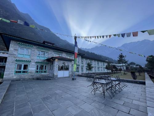 Mountain Lodges of Nepal - Lukla في Lukla: مبنى به طاولات وكراسي في ساحة