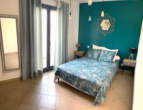 um quarto com uma cama e uma parede azul em Bel Appartement en plein cœur de Folelli em Penta-di-Casinca