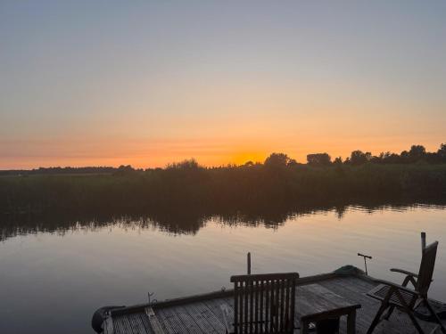 a sunset over a lake with a wooden dock at Luxe en ruim chalet met airco bij Leekstermeer in Matsloot