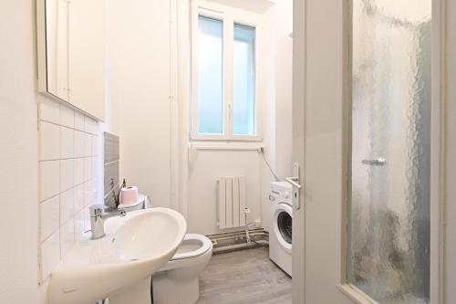 y baño blanco con lavabo y lavadora. en L'Instant Présent - Appt pour 4 en Charleville-Mézières