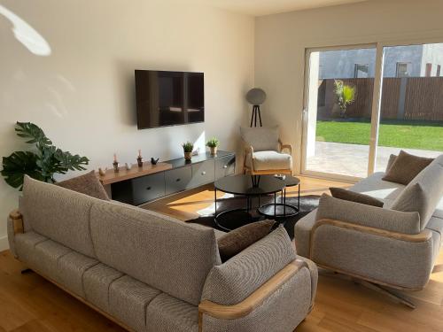 sala de estar con sofá, 2 sillas y TV en Maison moderne à Carbon Blanc, en Carbon-Blanc