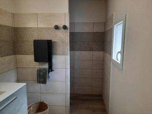 a bathroom with a shower with a television on the wall at L'Ardétente - Le cosy, Piscine et SPA en Ardèche, Adults only in Lussas