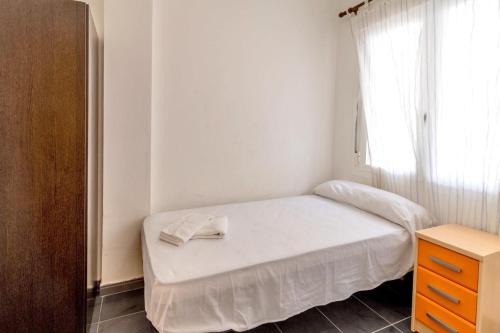 ein kleines Schlafzimmer mit einem weißen Bett und einem Fenster in der Unterkunft Cau del Llop 691 Apto con piscina comunitario in Llança