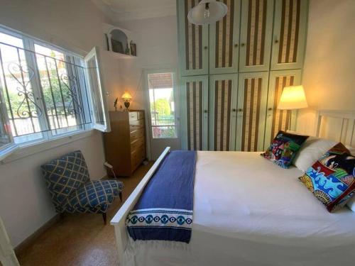 1 dormitorio con 1 cama, 1 silla y ventanas en Lovely House with Private Carport & Shady Veranda, en Atenas