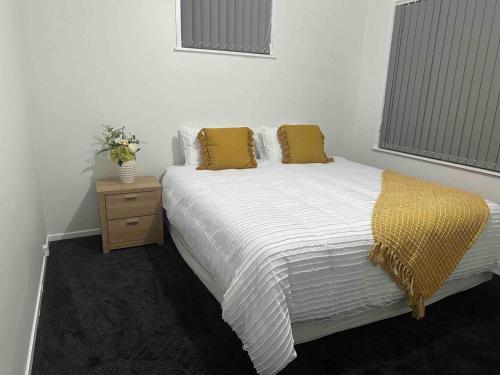 a bedroom with a white bed with yellow pillows at Cozy 3BR West Auckland in Auckland