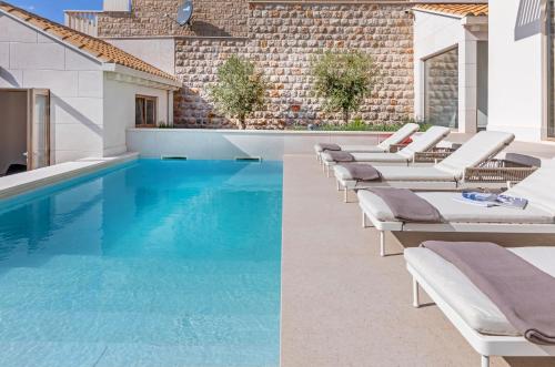 une piscine avec des chaises longues et une piscine dans l'établissement Brand New Villa Carmelita Exclusive with free Smart Car, à Dubrovnik