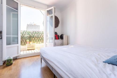 a bedroom with a white bed and a large window at Joli 2 pièces avec balcon. in Boulogne-Billancourt