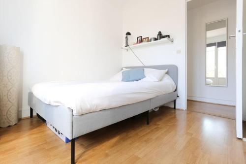 a white bed in a room with a wooden floor at Joli 2 pièces avec balcon. in Boulogne-Billancourt