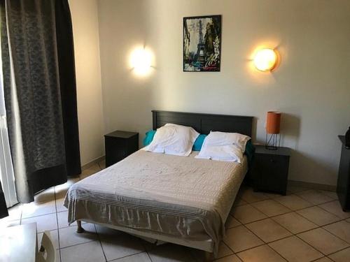 ein Schlafzimmer mit einem Bett mit zwei Nachttischen und zwei Lampen in der Unterkunft Résidence Hôtel Residella in Gémenos