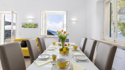 a dining room with a white table and chairs at VILLA MERAVIGLIA 8, Emma Villas in Nisporto