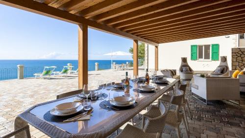 a dining table with plates and utensils on a patio at VILLA MERAVIGLIA 8, Emma Villas in Nisporto