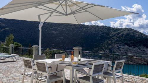 a white table and chairs with an umbrella at VILLA MERAVIGLIA 8, Emma Villas in Nisporto