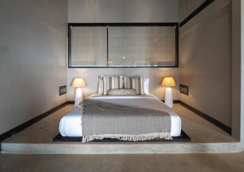 a bedroom with a large bed with two lamps at Red Thread Morjim in Morjim