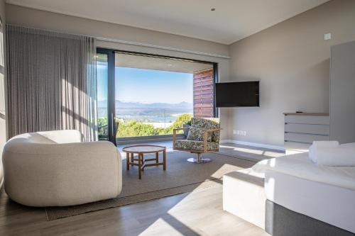 a living room with a white couch and a chair at Hilltop Bayview Luxury Apartments in Plettenberg Bay