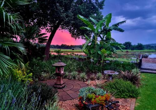a bird bath in a garden with a sunset in the background at Imbabali Retreat & Venue in Magaliesburg