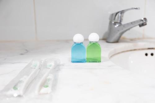 duas garrafas de escovas de dentes sentadas ao lado de um lavatório em Kirei Inn em Nagoya