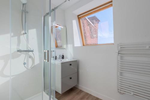 a white bathroom with a shower and a window at 1 bedroom duplex apartment, with parking in Tourcoing