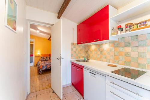 une cuisine avec des placards rouges et un salon dans l'établissement Mazet à Nimes, à Nîmes