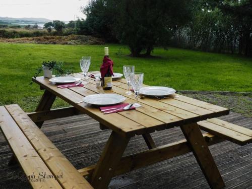 una mesa de picnic de madera con una botella de vino y copas en Stonechat Cottage - Portmagee en Portmagee
