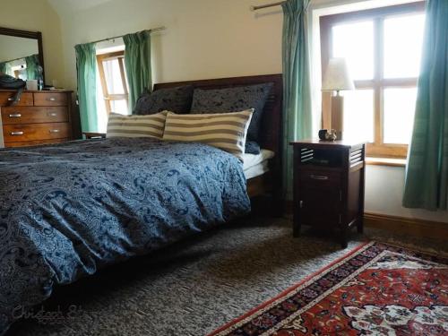 1 dormitorio con 1 cama, vestidor y ventanas en Stonechat Cottage - Portmagee en Portmagee