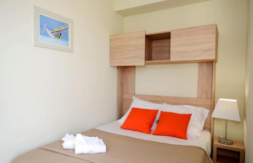 Sallèles-dʼAudeにあるRésidence Odalys Côté Canalのベッドルーム1室(オレンジ色の枕2つ、ベッド1台付)