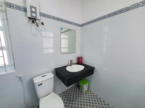 uma casa de banho com um WC branco e um lavatório. em Vườn Quốc Gia U Minh Hạ em Xóm Mũi