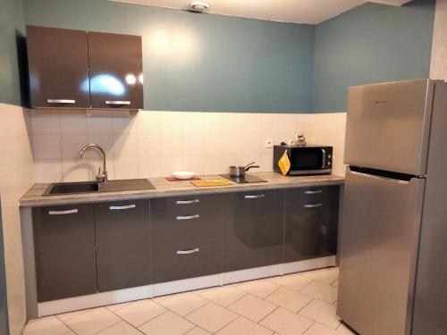 eine Küche mit einem Kühlschrank aus Edelstahl und einer Mikrowelle in der Unterkunft Ferme de l'Etang - Gîte in Épuisay