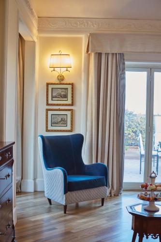 a blue chair in a living room with a window at Villa Sant'Andrea, A Belmond Hotel, Taormina Mare in Taormina