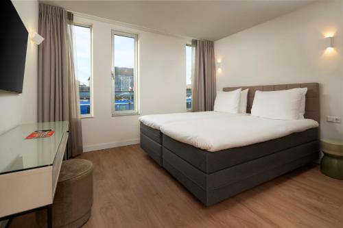 um quarto de hotel com uma cama e duas janelas em WestCord Art Hotel Amsterdam 4 stars em Amsterdã