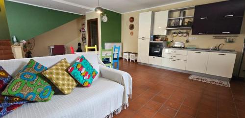 Bb24 - Casa Sul Fiume في Pianello: غرفة معيشة مع أريكة بيضاء مع وسائد ملونة