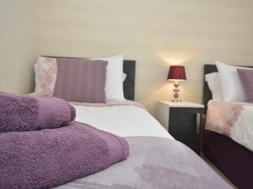 um quarto com 2 camas com almofadas roxas e brancas em 2 Bed in Tattershall Lakes 50360 em Tattershall
