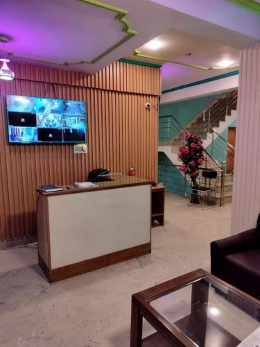 a lobby with a reception desk and a tv on a wall at Hotel Foothills , Srinagar in Srinagar