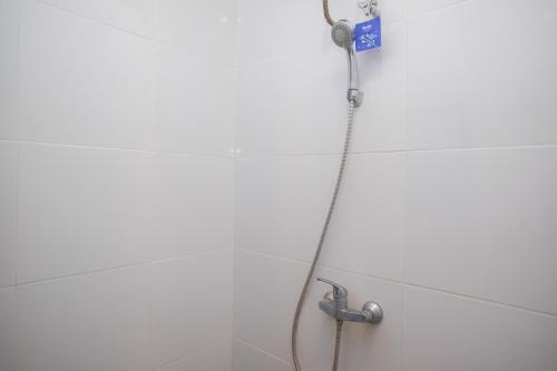 a shower with a hose attached to a wall at RedDoorz near Stasiun Solo Balapan 3 in Bonorejo