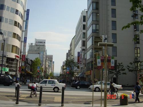 a busy city street with cars and people crossing the street at Mimatsuso Ryokan in Asahikawa