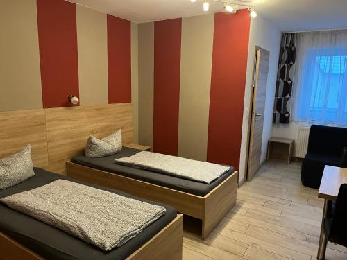 2 łóżka w pokoju z czerwonymi i żółtymi paskami w obiekcie Haus Roseneck-Pension Am Stadtrand w mieście Borchen