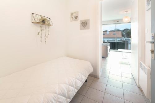 une chambre blanche avec un lit blanc et une fenêtre dans l'établissement Les Roses, Studio, à Pornichet